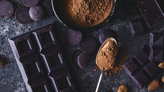 Coacoa, dark chocolate bar, and dark chocolate button on a black table