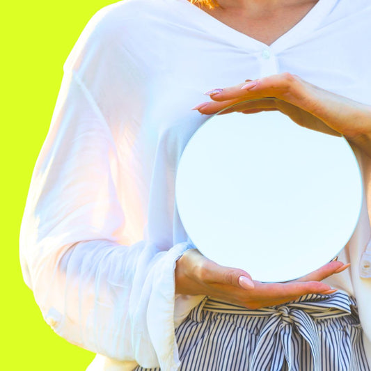 Woman holding mirror in front of body