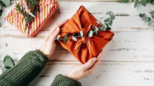 Gifts wrapped in orange cloth with leafy decorations