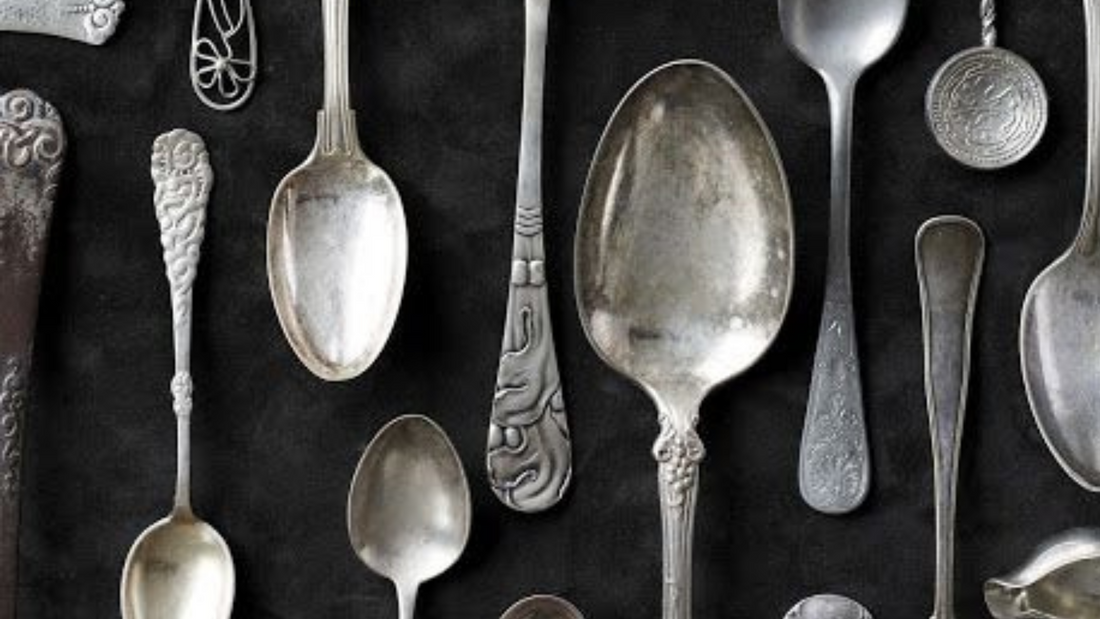 Silver spoons of different sizes and design laid down on a black table