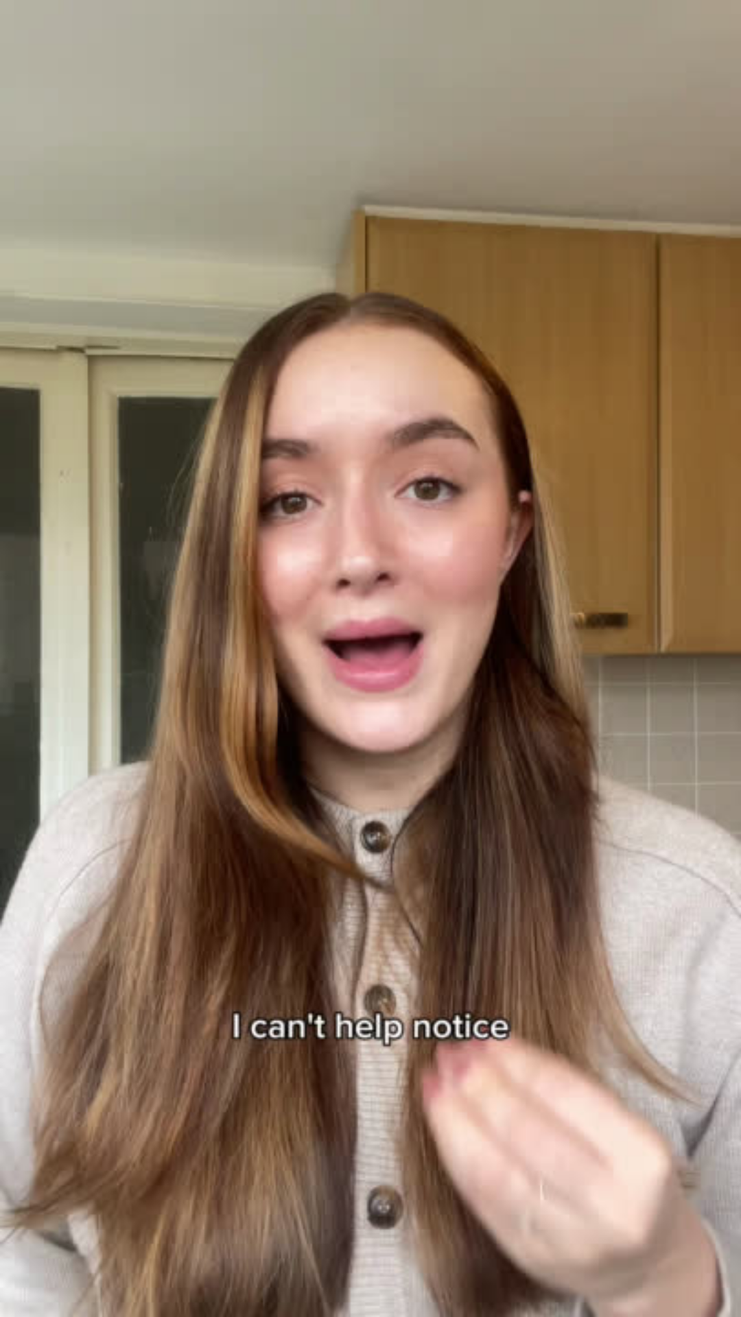 Woman with light brown hair standing in a kitchen talking to camera saying I can't help notice