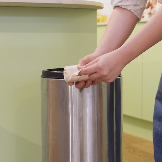 Unrolling of 30 litre biodegradable bin bag and putting it inside a kitchen bin