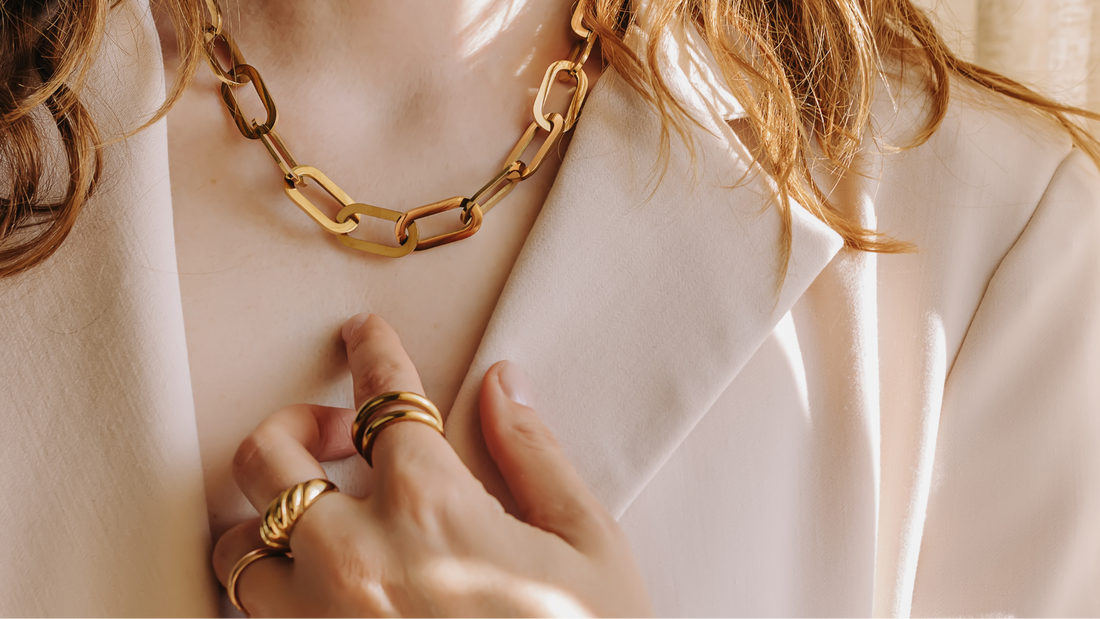 Close up of gold chain necklace and gold rings on woman
