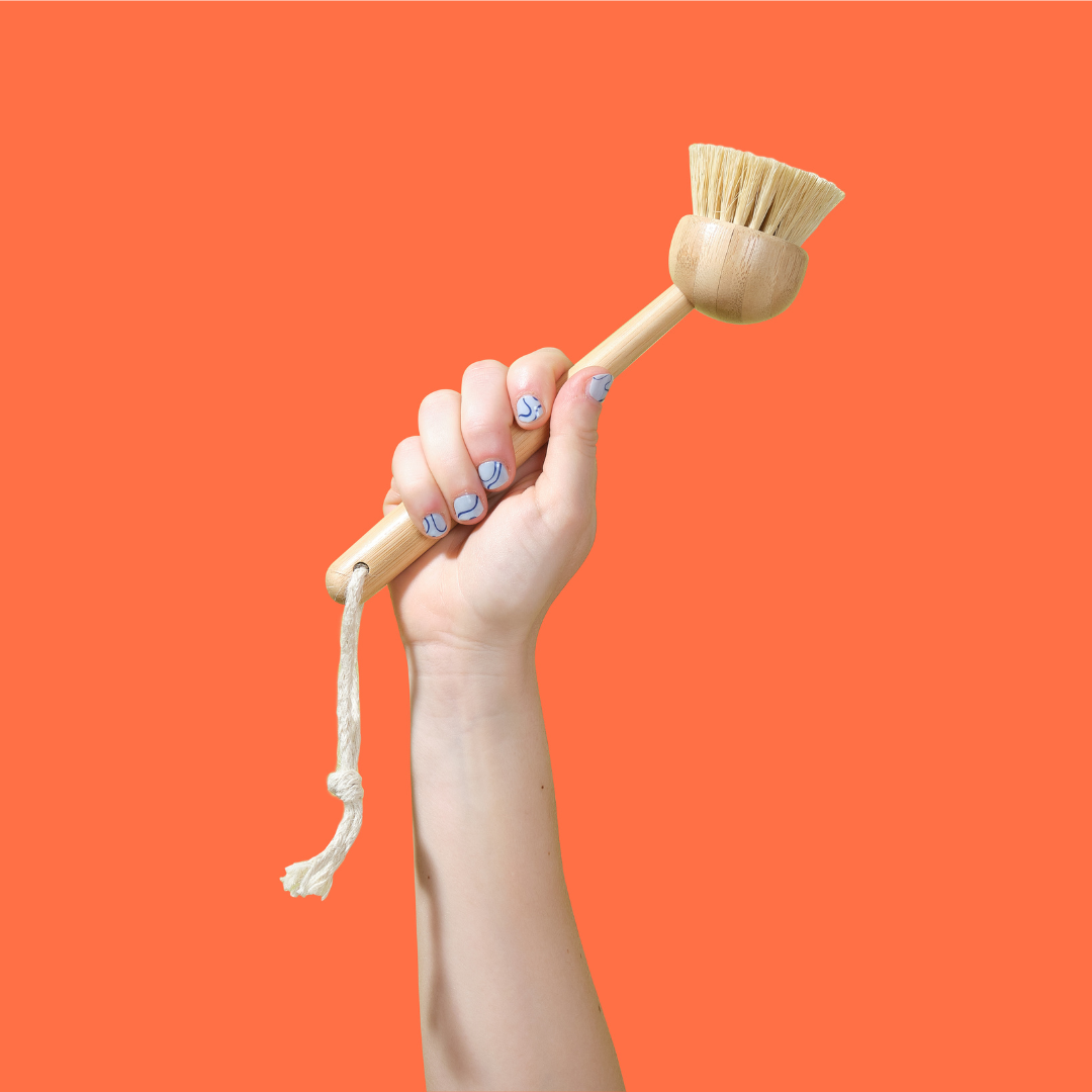 Hand holding bamboo dish brush upwards