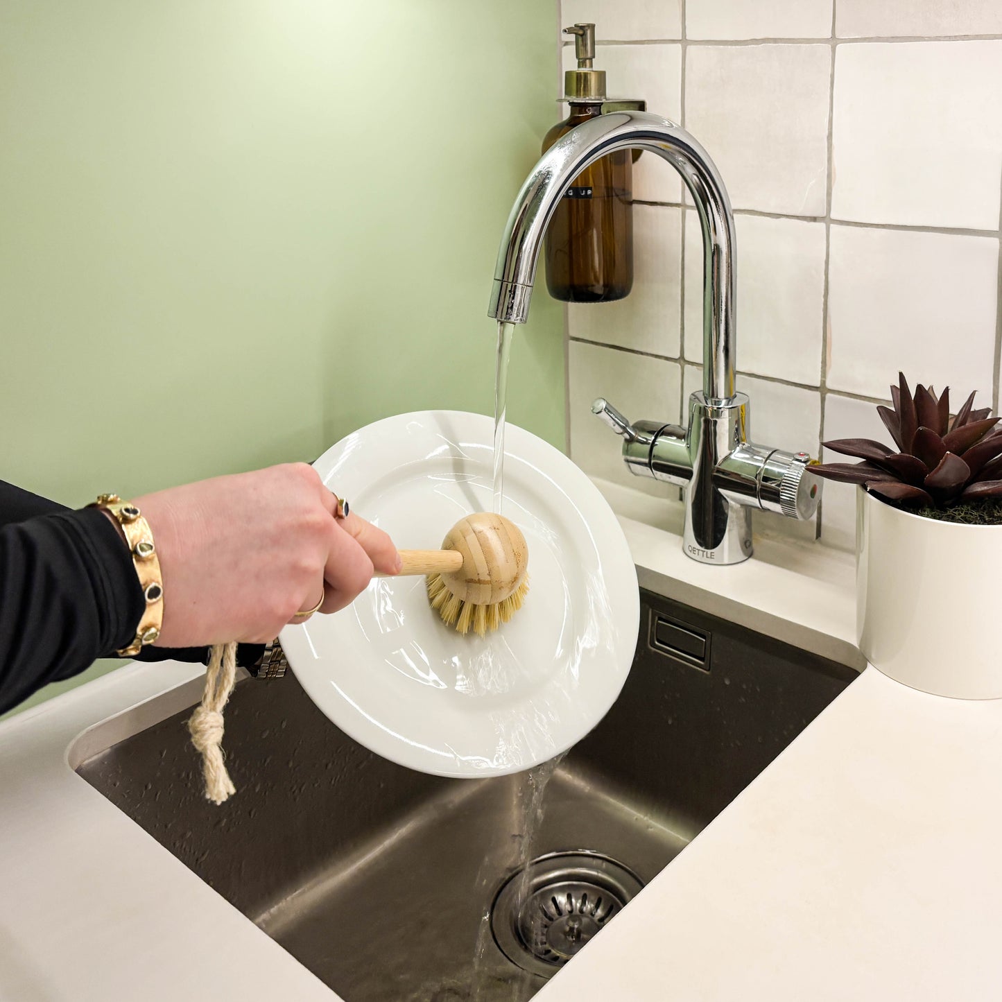 Person washing up plate with bamboo brush