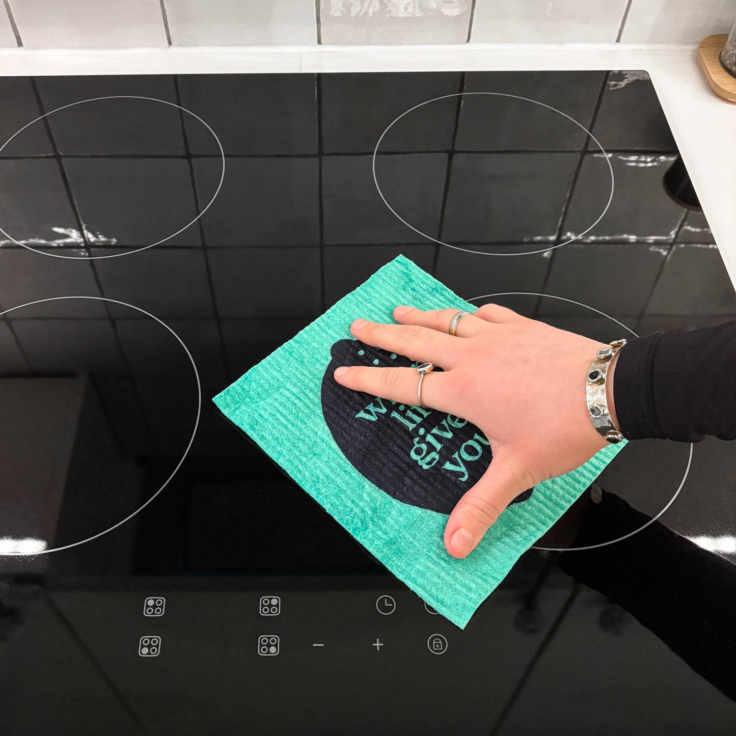 Person cleaning stove with sponge cloth