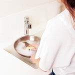 Woman washing up a pan with eco kitchen sponge