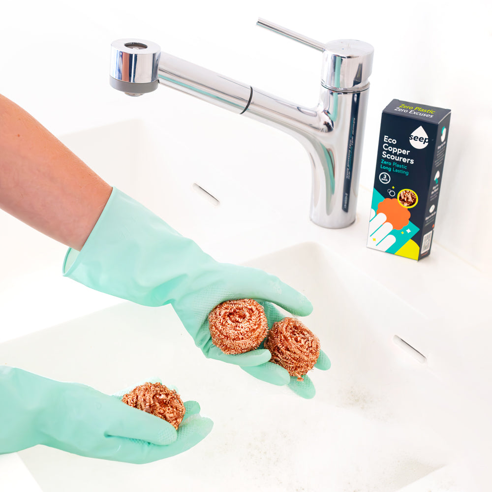 Three Recyclable Copper Scourers being used in kitchen sink with packaging displayed